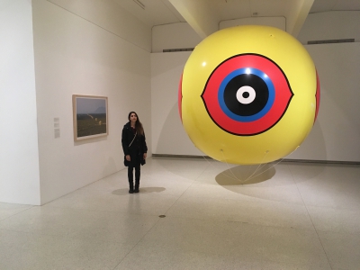 Nicole standing next to an art exhibit - a bright yellow round subject that takes up space from floor to ceiling